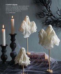 three candles and some fake ghost decorations on a table