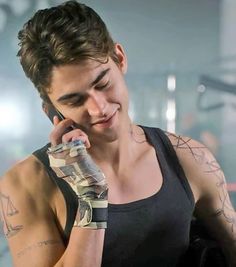 a man with tattoos on his arm talking on a cell phone