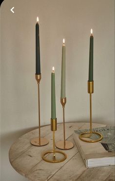 three candles sitting on top of a wooden table next to a book and candle holder