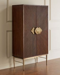 a wooden cabinet sitting on top of a hard wood floor next to a white wall