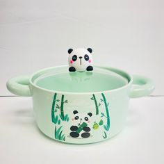 a panda bear sitting on top of a green casserole with bamboo trees in the background