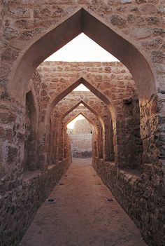 an archway leading to another building with stone walls and brick flooring, in the desert