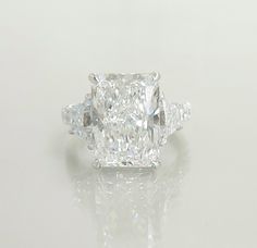 a fancy diamond ring with three stones on the band and an oval cut center stone