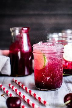 a jar filled with liquid next to two red and white striped strawberries on a table