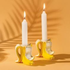 two banana candles sitting next to each other on top of a yellow tablecloth covered floor