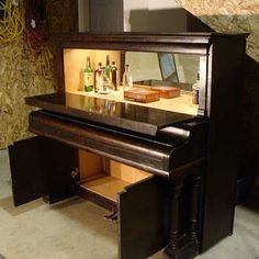 a piano that is sitting in front of a wall with some bottles on top of it