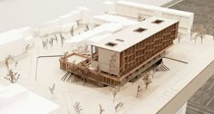 an architectural model of a building on top of a white surface with trees in the foreground