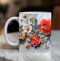 a marble coffee mug with orange and white flowers painted on the side, sitting on a table