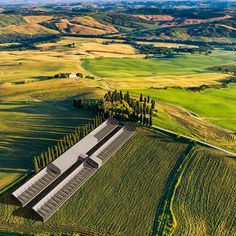 an aerial view of a farm in the middle of a green field with trees and rolling hills