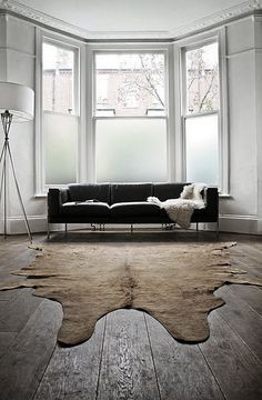 a living room filled with furniture and a large rug on top of a hard wood floor