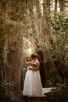 two brides hugging in the woods on their wedding day