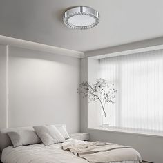 a white bedroom with a bed, nightstands and window in the corner is lit by a round light fixture