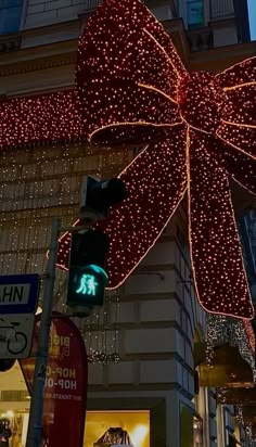 a large christmas bow hanging from the side of a building in front of a traffic light