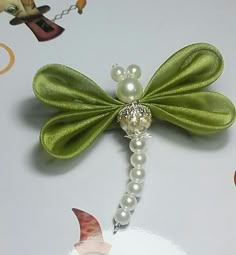 a green dragon brooch with pearls on it's tail and attached to a beaded necklace