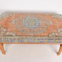 an orange and blue rug on top of a wooden bench with two legs in front of it