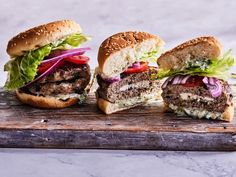 three hamburgers with lettuce, tomato and onion