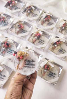 a person holding up a small piece of cake in front of many other plates with flowers on them