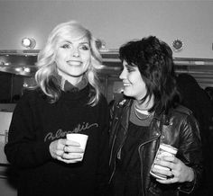 two women standing next to each other holding drinks