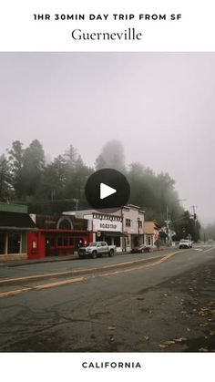 an image of a street with cars parked on the side and foggy trees in the background