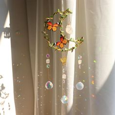 a wind chime hanging from a curtain with butterflies on it