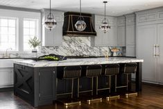 a large kitchen with marble counter tops and black cabinets, along with gold trimmings