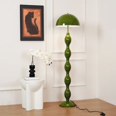 a green lamp sitting on top of a wooden floor next to a white toilet in a room