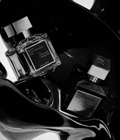 black and white photograph of various perfumes on display in a glass bowl, including an eau de toilette