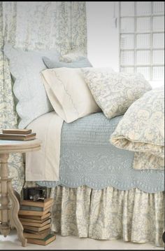 a bed with blue and white bedspread next to a table filled with books