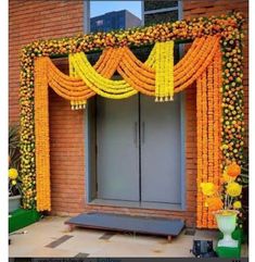 an entrance decorated with yellow flowers and orange garlands for a wedding or special occasion