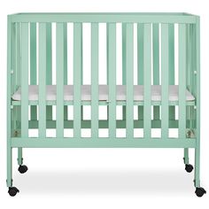 a baby crib that has wheels on the bottom and sides, in mint green