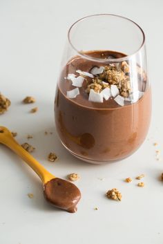 a glass filled with chocolate and marshmallows next to a spoon