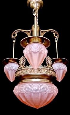 a pink and gold chandelier hanging from a ceiling fixture with four lights on it