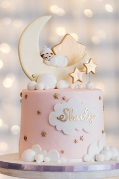 there is a pink cake with stars and a baby on it