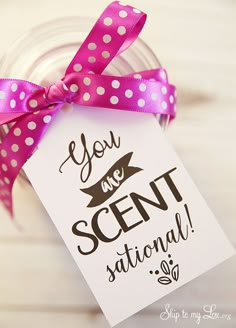 a pink and white polka dot ribbon tied around a tag with the words you are scent station on it