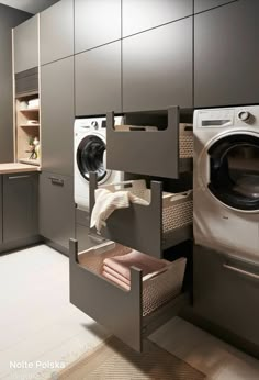 a washer and dryer in a small room with grey cabinets, white tile flooring