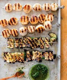 grilled chicken and vegetable skewers with pesto sauce on a baking sheet