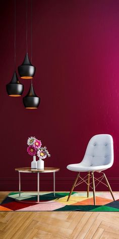 two chairs and a table in a room with red walls, wooden floors and colorful rugs