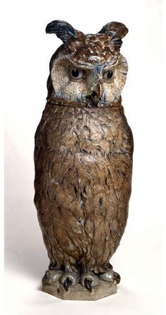 an owl figurine sitting on top of a wooden stump in front of a white background