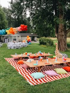 an outdoor party with giraffes and balloons on the grass in front of a tree