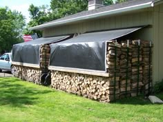 a truck is parked in front of a house with wood stacked on the side and an awning over it