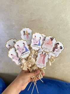 a person holding up some pictures on top of a blue cushion with pins in it