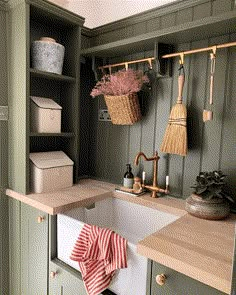 a kitchen with green cabinets and a white sink in the center, next to an open cupboard