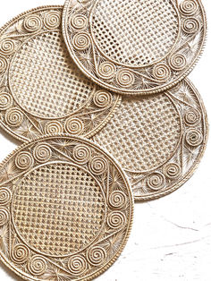 four woven coasters are shown on a white tablecloth with an intricate design in the middle