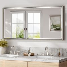 a bathroom with double sinks and large mirrors