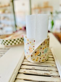 a roll of toilet paper sitting on top of a wooden table next to a window