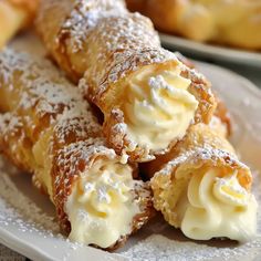 several pastries on a white plate with powdered sugar and icing around them