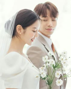 the bride and groom are looking at each other with flowers in front of their faces