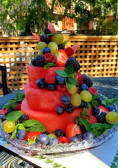 a watermelon cake with berries and leaves on top