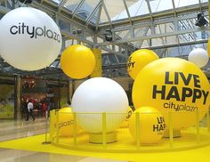 large yellow and white balloons with live happy words on them in an indoor shopping mall