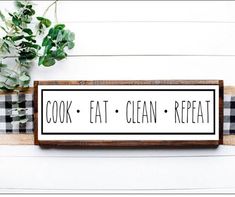 a sign that says cook eat clean repeat on it next to a potted plant